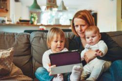 niñera con dos niños mirando tablet