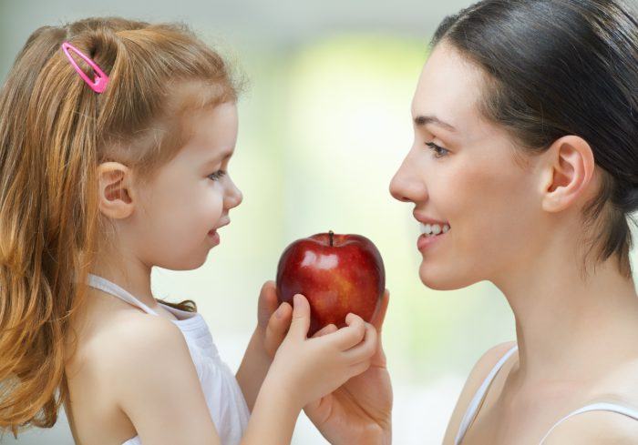 cómo ser una buena cuidadora de niños, niñera dando manzana a niña