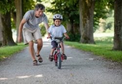 Cómo prevenir accidentes infantiles, niño montando en bicicleta con casco y su padre